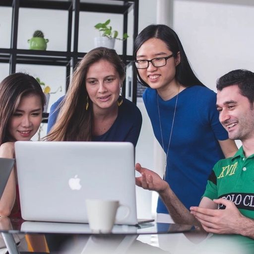 a group of people are looking at a laptop computer .