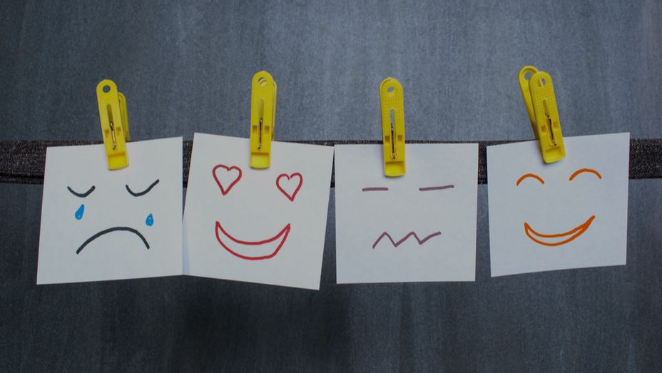 a row of sticky notes with different facial expressions hanging on a clothes line .