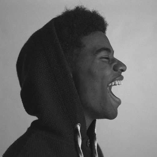 a black and white photo of a young man wearing a hoodie laughing .