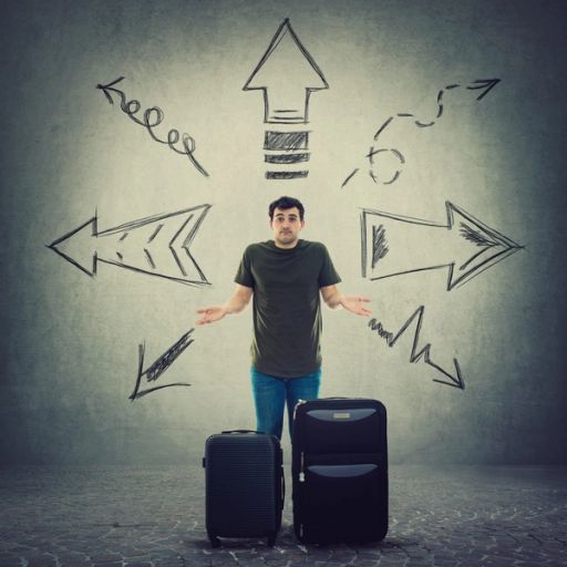 a man is standing with two suitcases in front of a wall with arrows drawn on it .