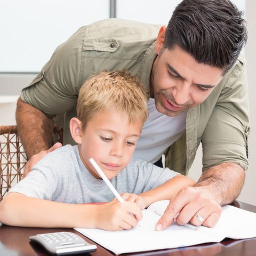 a man is helping a young boy with his homework at a table .