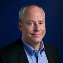 a man in a suit and blue shirt smiles for the camera