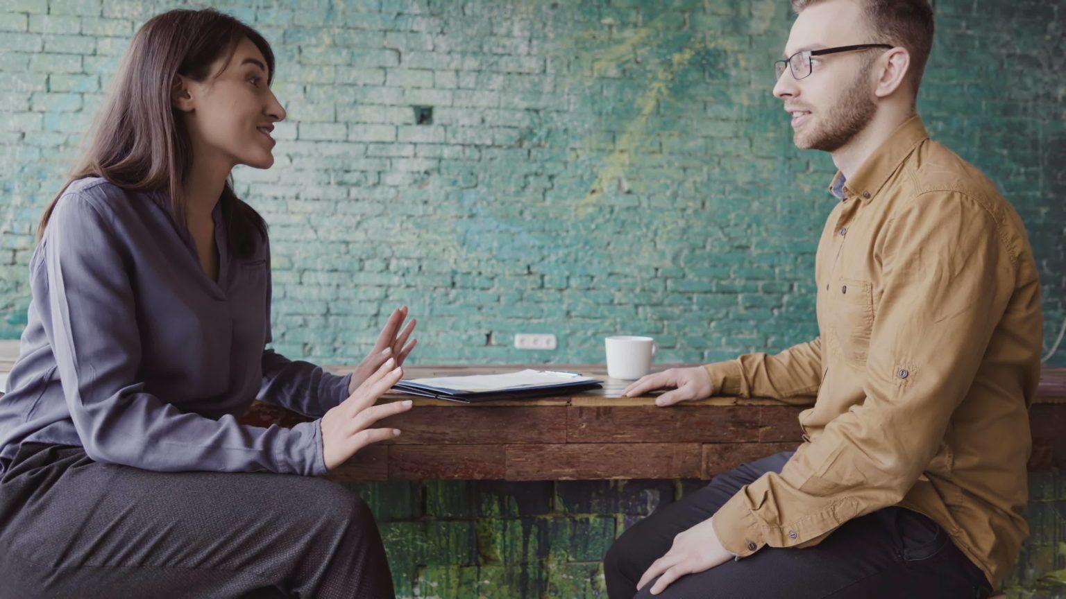 a man and a woman are sitting at a table having a conversation .