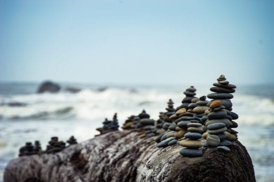 a pile of rocks stacked on top of a log on the beach .
