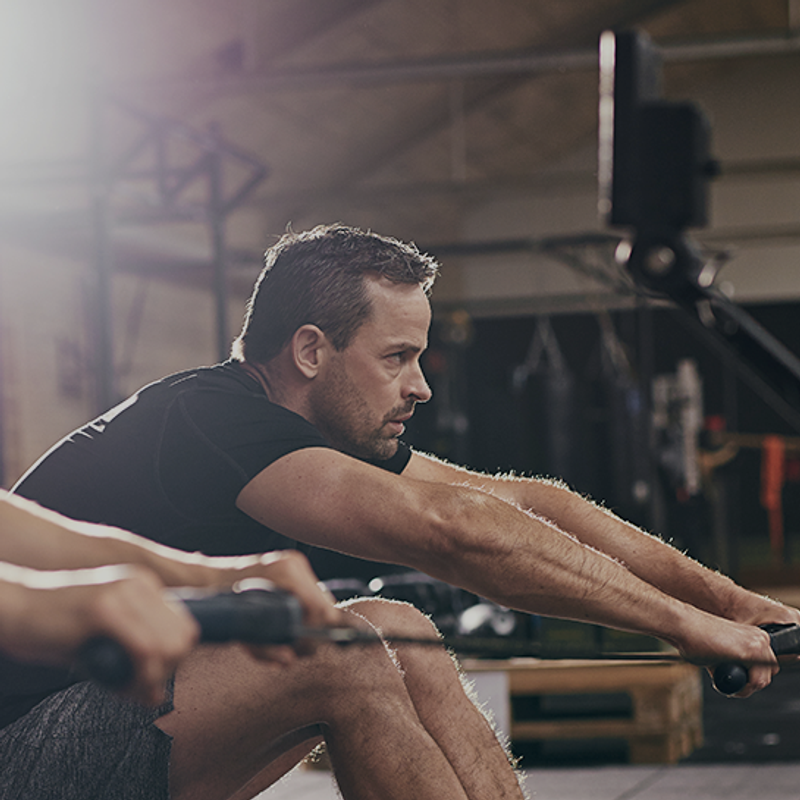 The top biohacks to unleash peak well-being image of man on rowing machine in gym