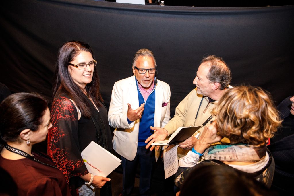 a group of people are standing around talking to each other .