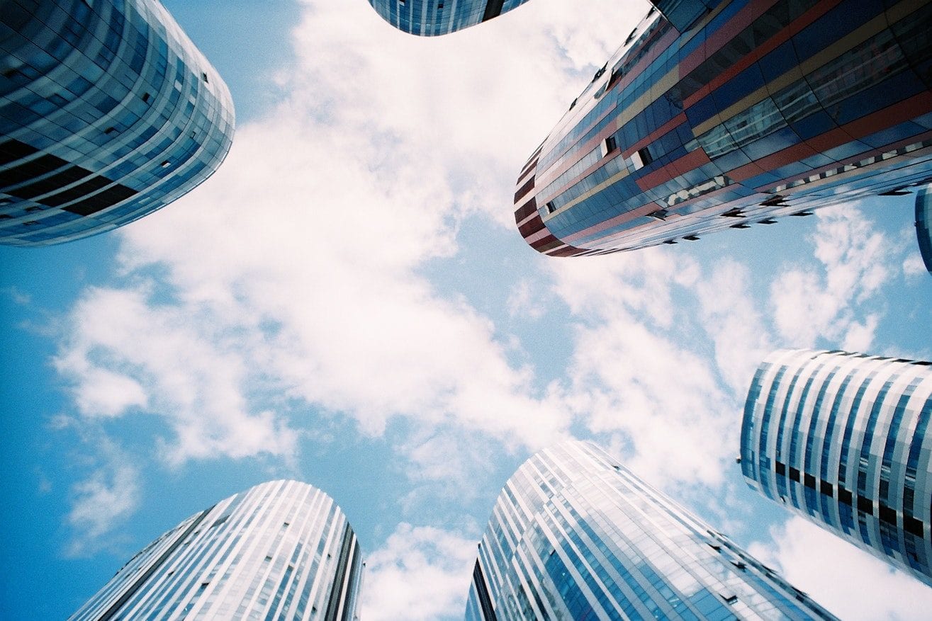 looking up at a group of tall buildings against a blue sky with clouds .