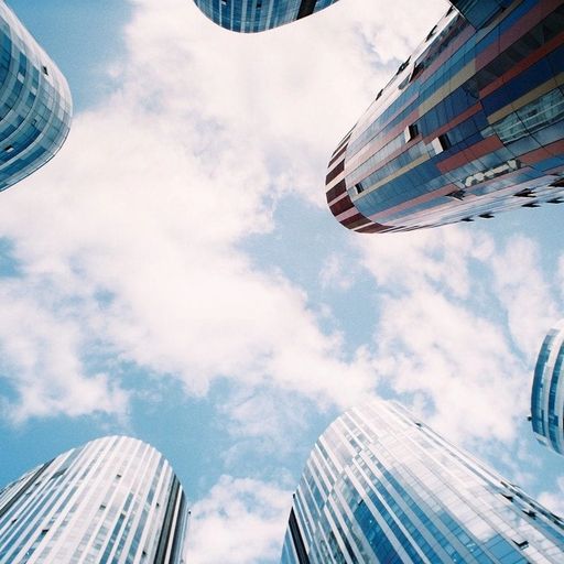 looking up at a group of tall buildings against a blue sky with clouds .