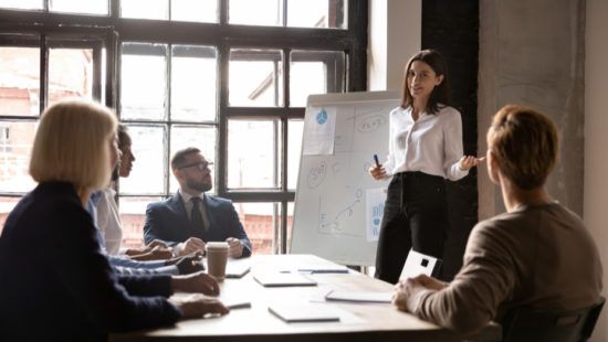 a woman is giving a presentation to a group of people sitting around a table .