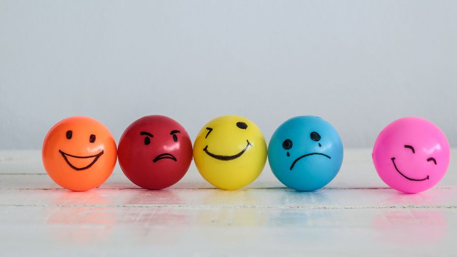 a row of colorful balls with smiley faces on them are sitting on a table .