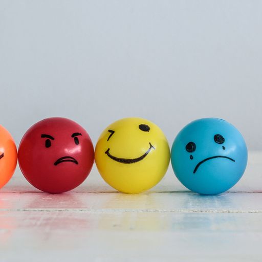 a row of colorful balls with smiley faces on them are sitting on a table .