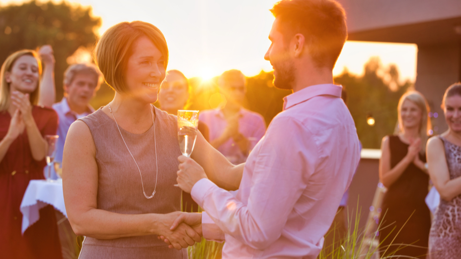 a man shakes hands with a woman holding a glass of champagne