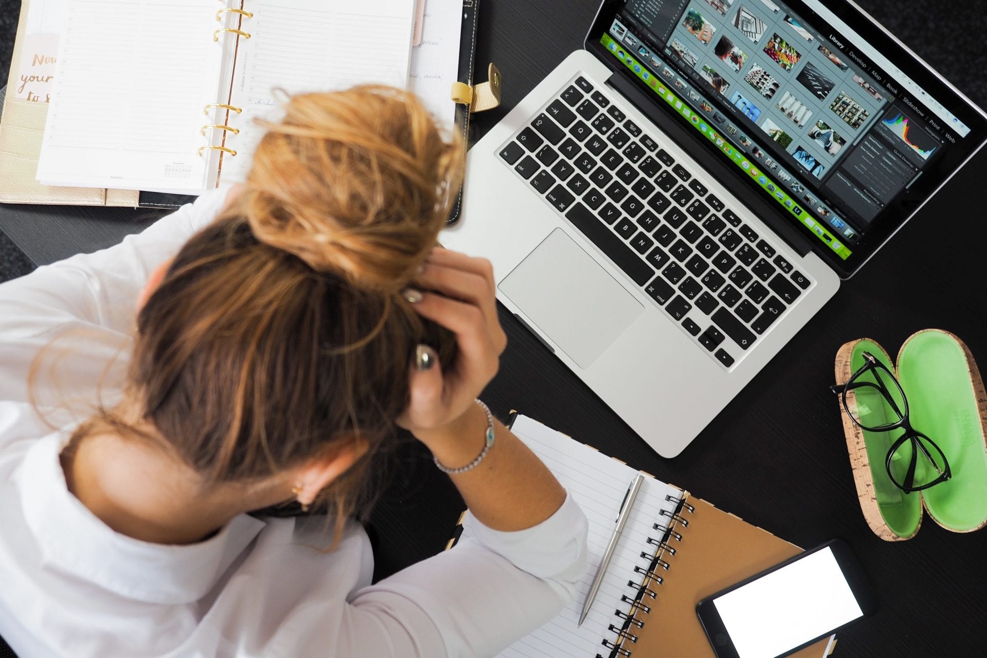 a woman is sitting at a desk with her head in her hands in front of a laptop computer .