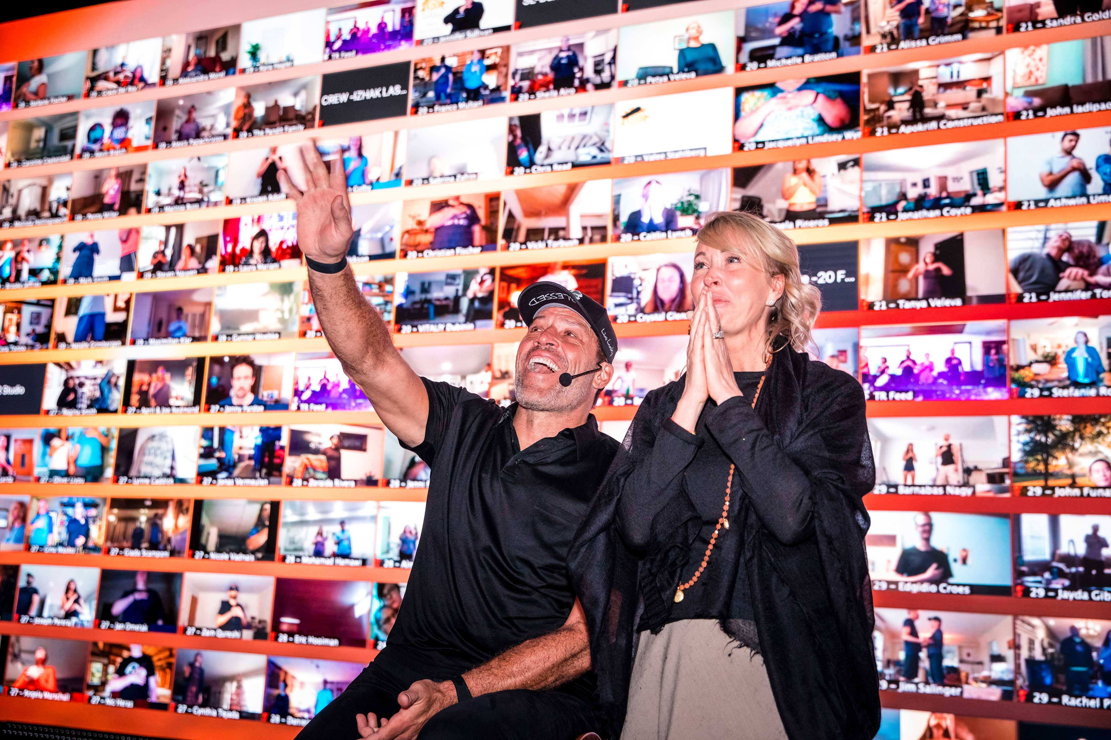 a man and a woman are standing in front of a large screen .