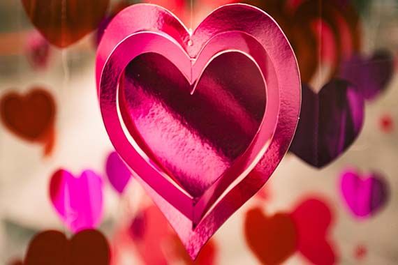 a pink heart is hanging from a string surrounded by other hearts .