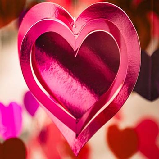 a pink heart is hanging from a string surrounded by other hearts .
