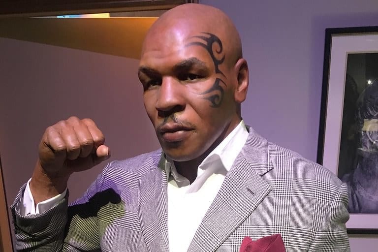 a wax figure of mike tyson is wearing a suit and a red pocket square .