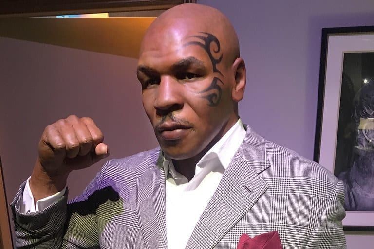 a wax figure of mike tyson is wearing a suit and a red pocket square .