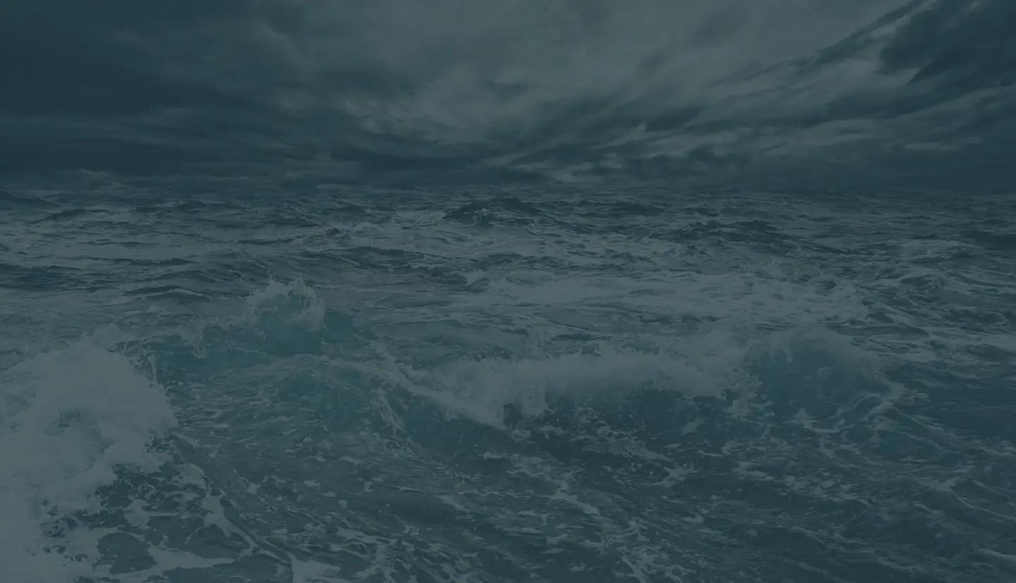a large body of water with waves crashing against a cloudy sky .
