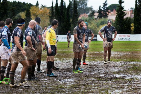 a group of rugby players are standing on a muddy field .