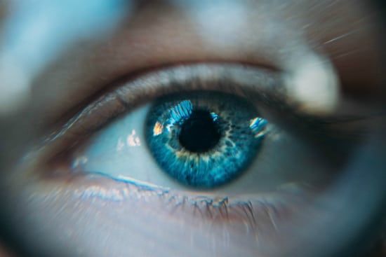 a close up of a person 's blue eye through a magnifying glass .