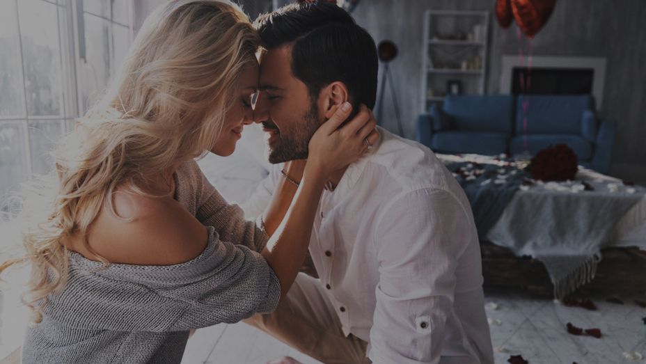 a man and a woman are kissing in a living room .