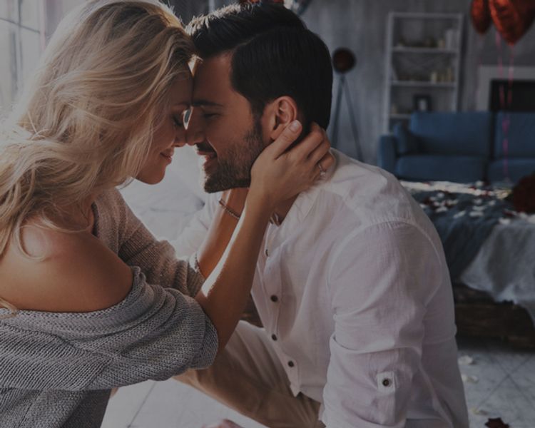 a man and a woman are kissing in a living room .