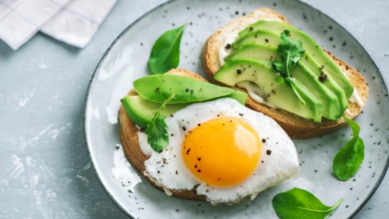 two slices of toast with avocado and a fried egg on a plate .