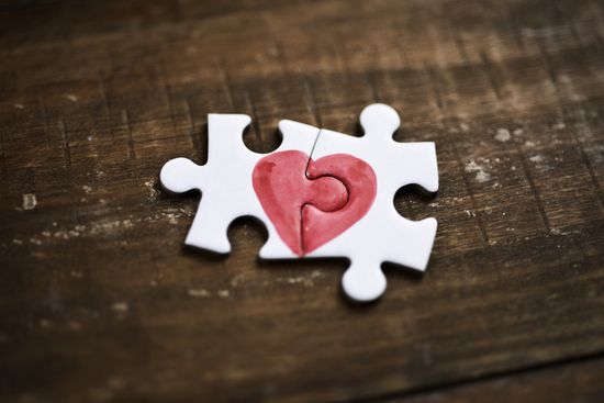 a puzzle piece with a heart drawn on it is sitting on a wooden table .
