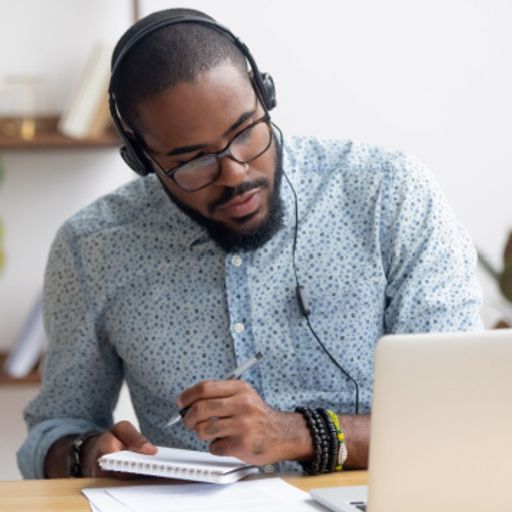 a man wearing headphones is sitting at a desk in front of a laptop computer .