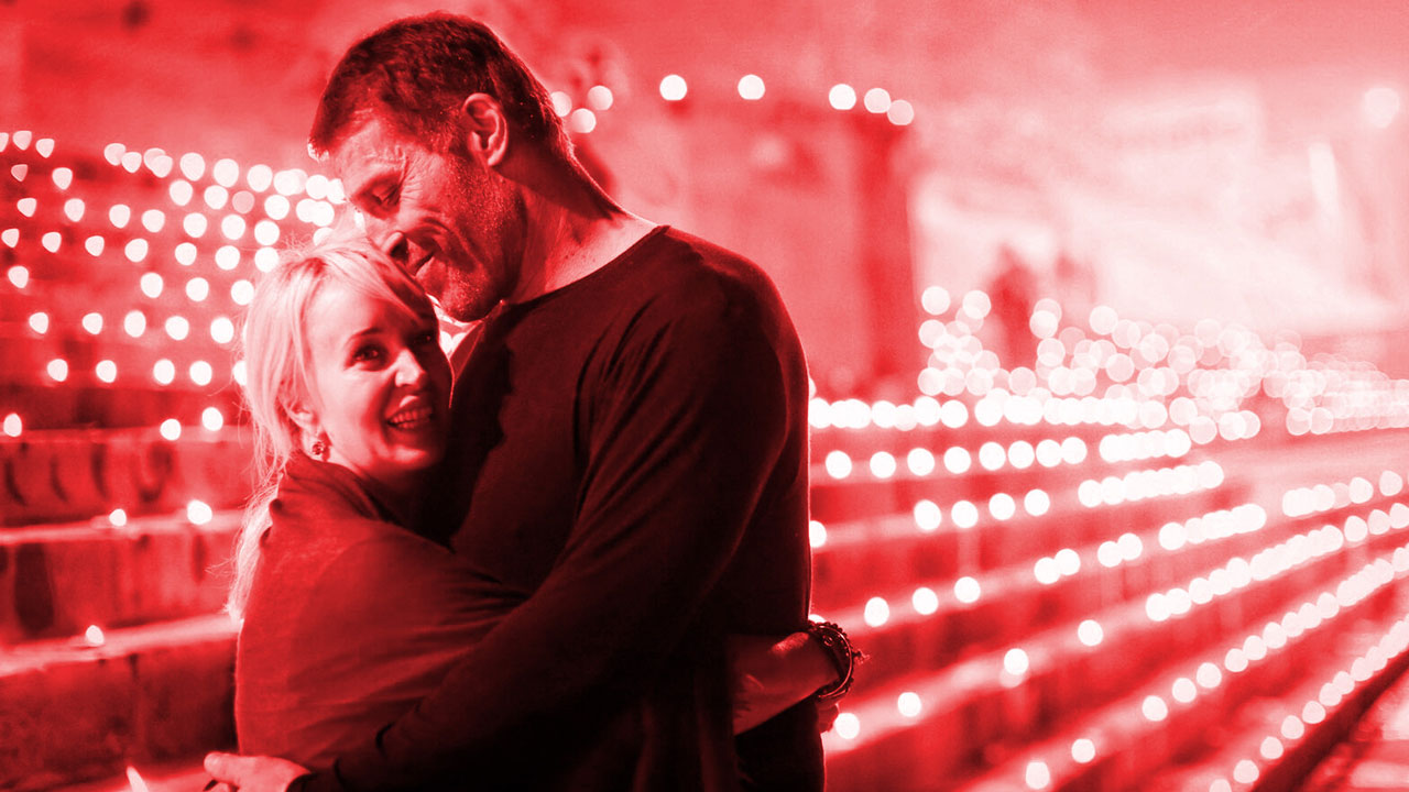 a man and woman are hugging in front of a red background