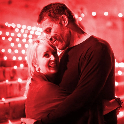 a man and woman are hugging in front of a red background