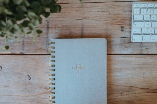 a notebook and a keyboard are on a wooden table .