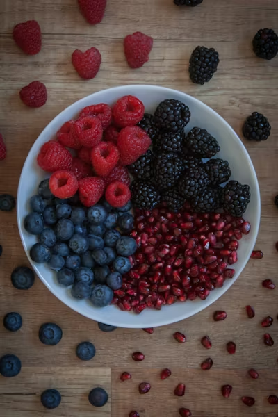 a white bowl filled with raspberries blueberries blackberries and pomegranate seeds