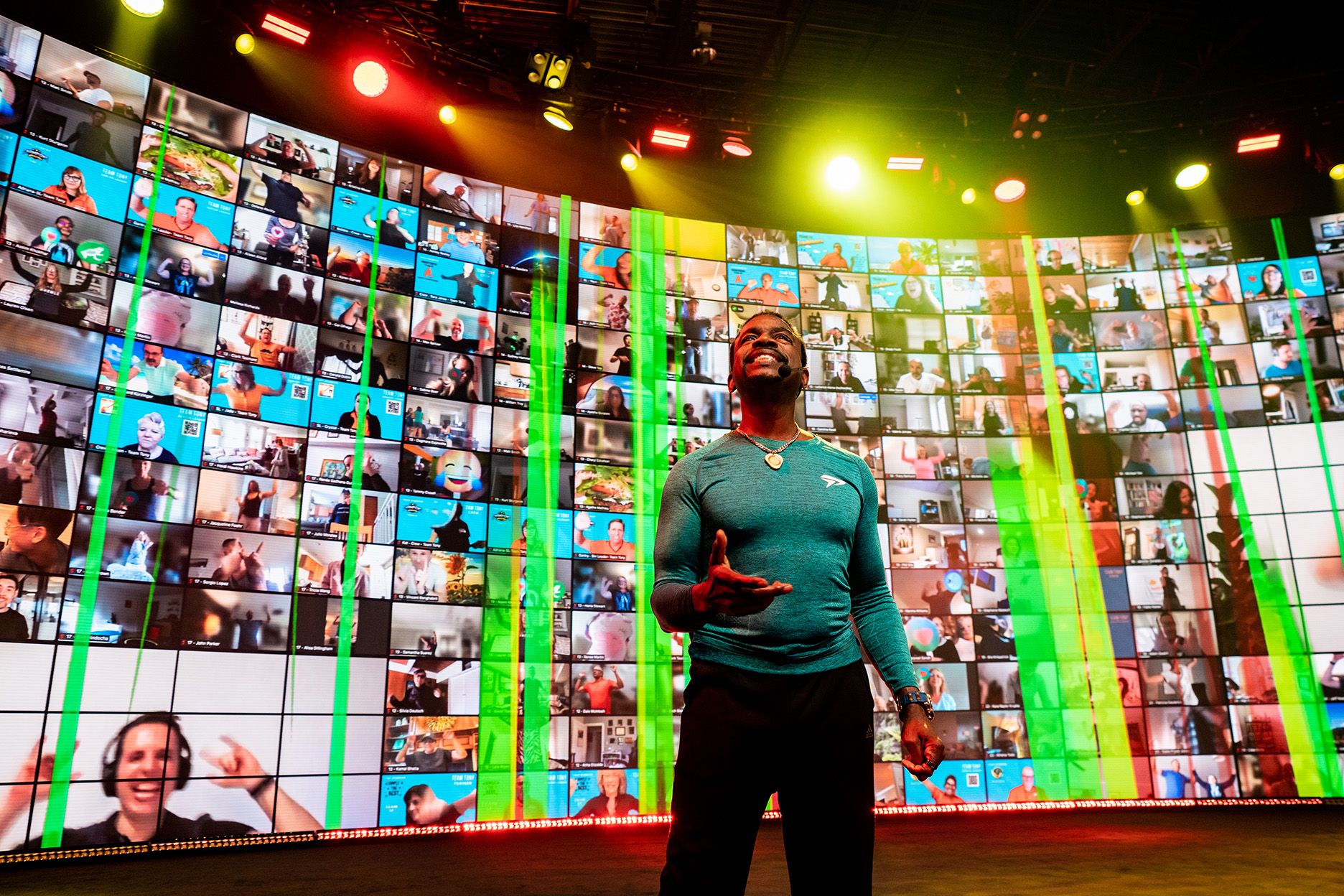 a man is standing in front of a large screen with a lot of people on it .