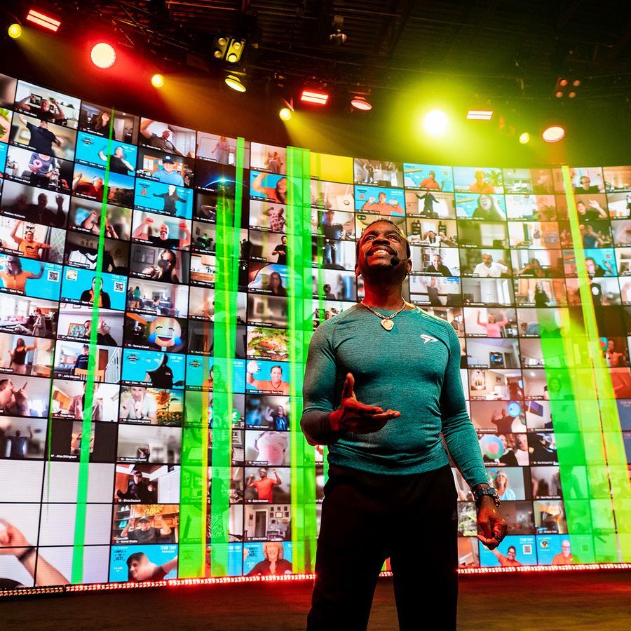 a man is standing in front of a large screen with a lot of people on it .