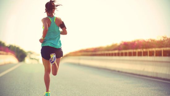 a woman is running on a highway at sunset .