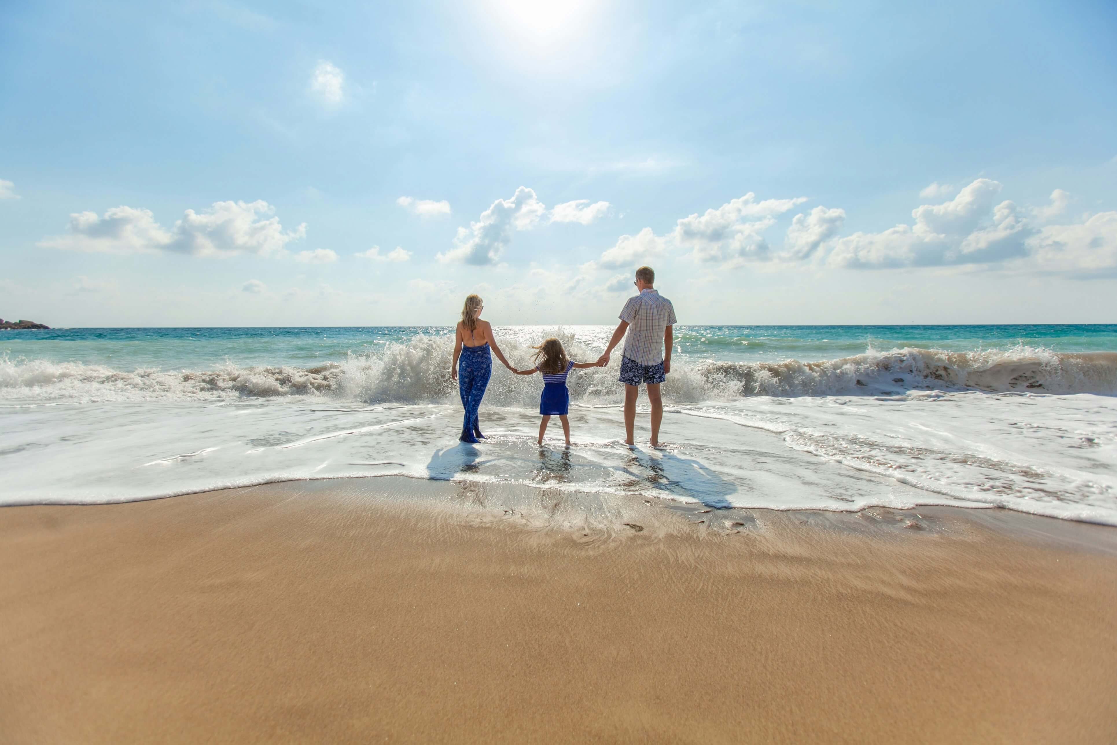 a family is walking on the beach holding hands .