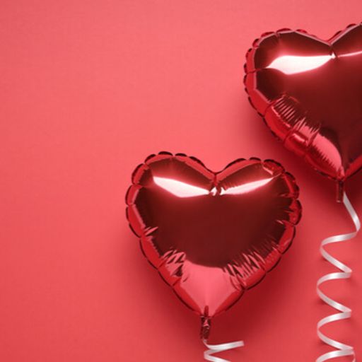 two red heart shaped balloons with a ribbon on a red background .