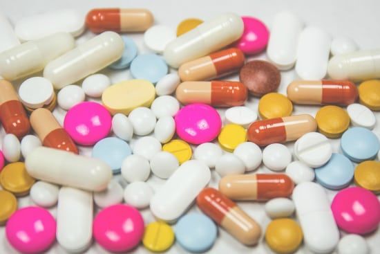 a pile of colorful pills and capsules on a white surface .
