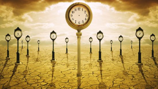 a clock on a pole in the middle of a desert surrounded by street clocks .