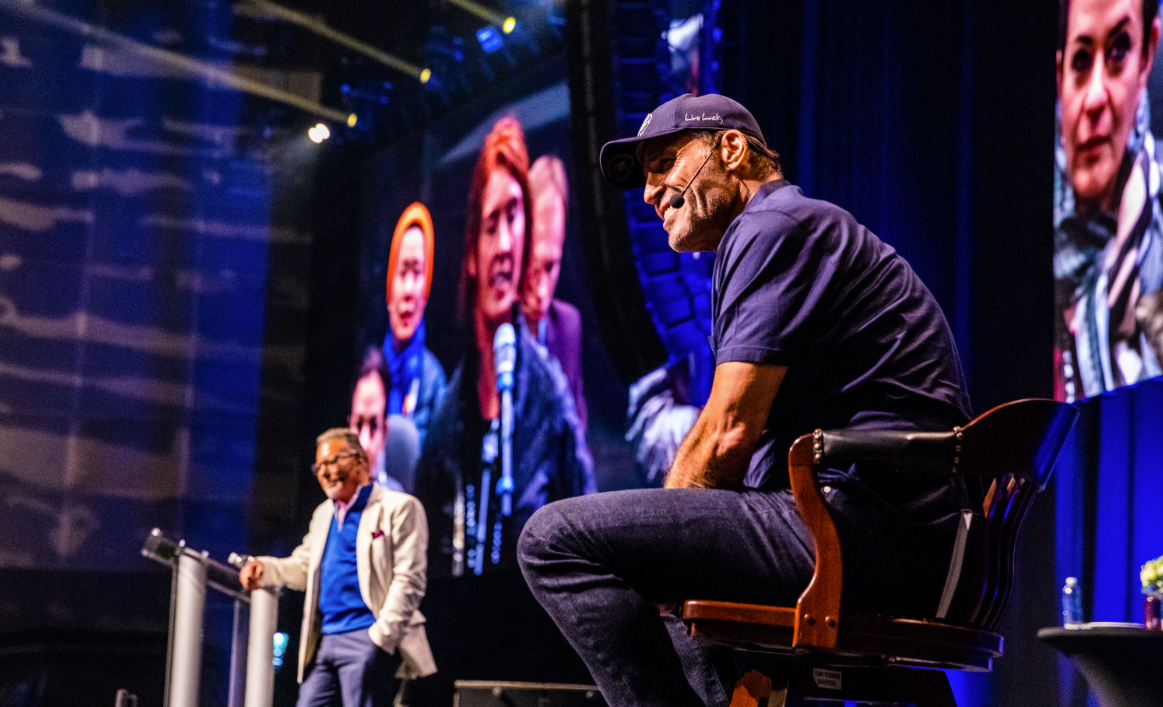 a man sitting in front of a screen that says ' new york ' on it