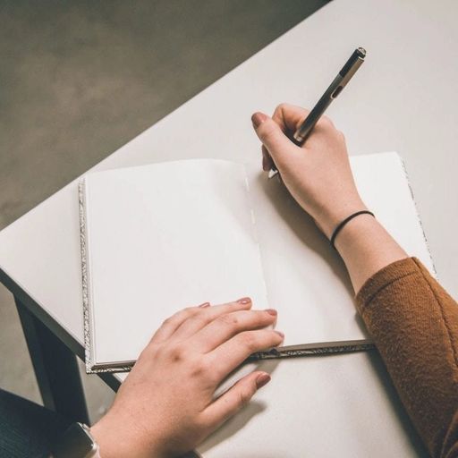 a person is writing in a notebook with a pen .