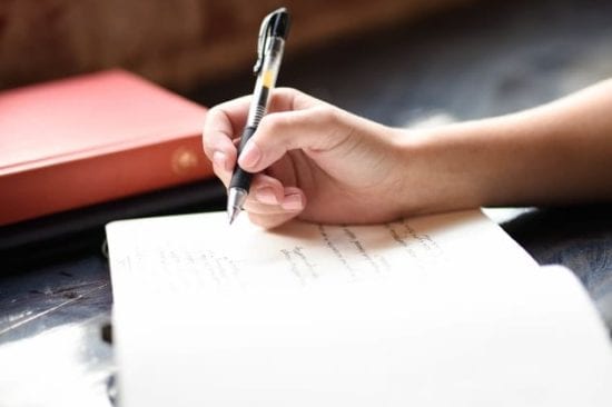 a person is writing on a piece of paper with a pen .