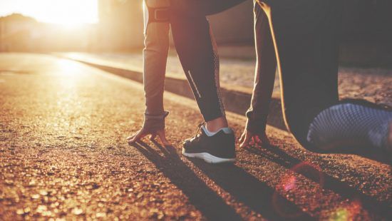 a person is getting ready to run on a road at sunset .