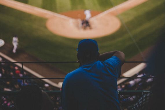 a man in a blue shirt is watching a baseball game from the stands .