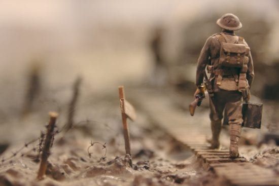 a miniature model of a soldier walking across a wooden bridge .