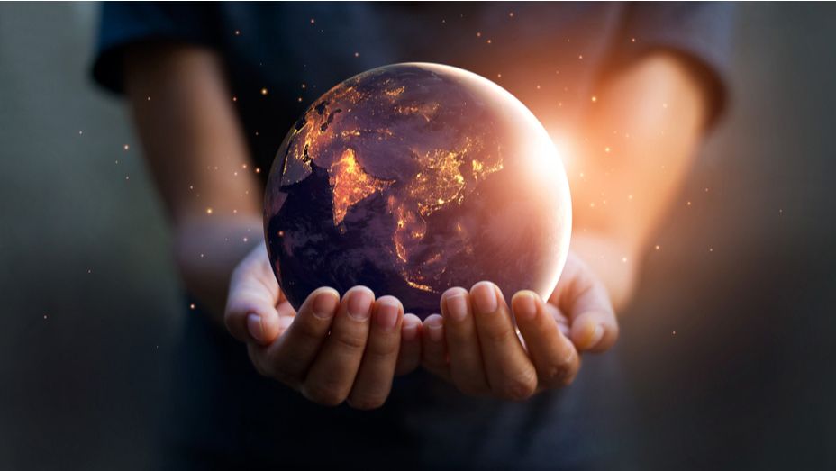 a person is holding a glowing globe in their hands .