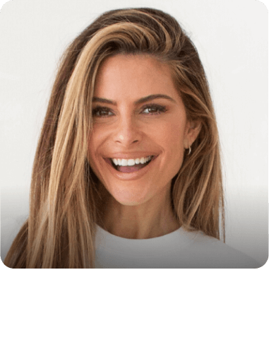 Maria Menounous with long blonde hair is smiling for the camera