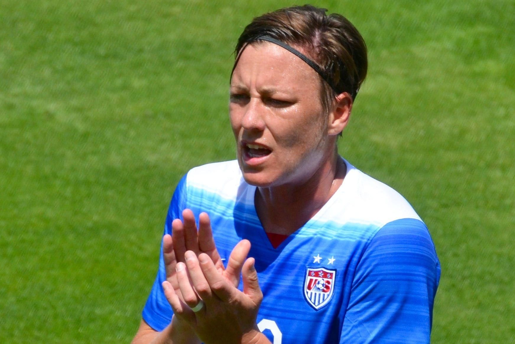 a female soccer player is clapping her hands on a field .